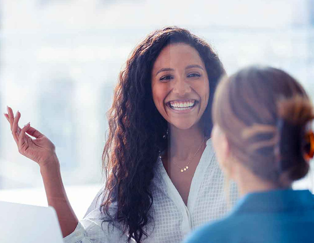 two co-workers talking and smiling